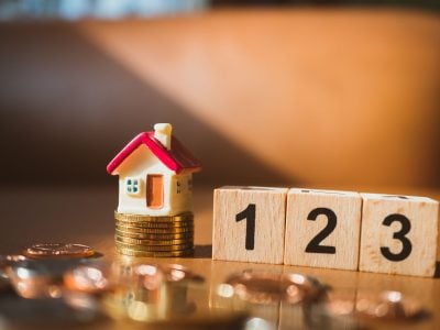 Miniature house on stack coins with wooden block number using as business and financial concept