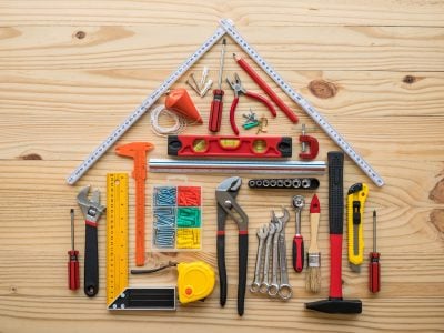 Flat lay of construction tools as house model on wooden background with copy space. New house construction, repair maintenance, DIY (Do It Yourself) and real estate property or finance loan concept.